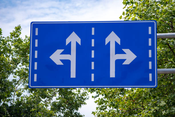 istock Two Way Road Sign with blue sky and trees 1415098695