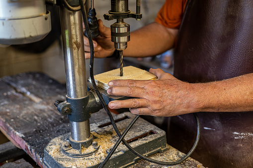 Details of the hands of a carpenter working at his space.