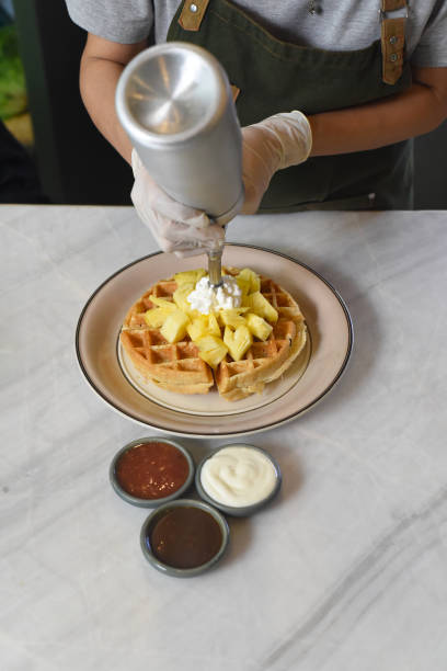 gelato versato a mano su waffle belgi con ananas a fette - human hand baked food pineapple foto e immagini stock