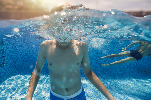 Split shot of teenage boys playing underwater in the swimming pool. \nCanon R5