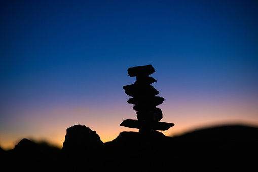 Silhouette Shale Rock Cairn at sunrise.  Rocks balanced stacked on top of each other silhouette at dawn dusk.