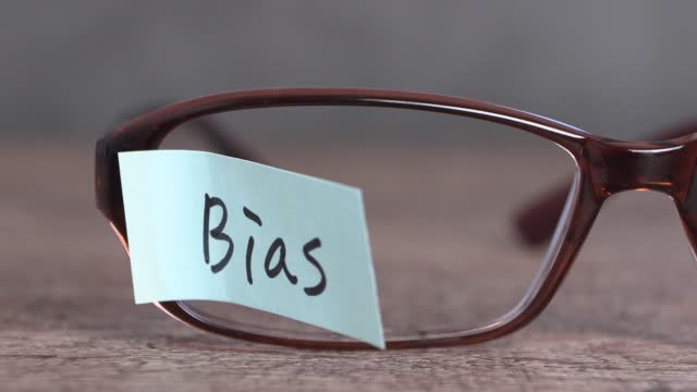 Pieces of paper and eyeglasses with a 'Bias' swaying in the wind.