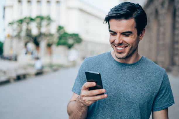 istock Young smiling man using smartphone on the street. 1415121812