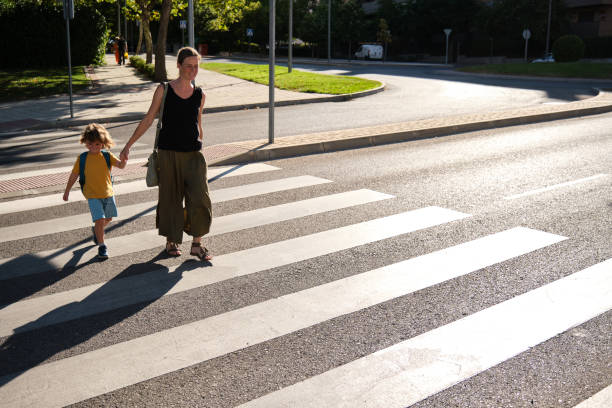 A Mother and her son crossing road on way to school Mother and her son crossing road on way to school pedestrian stock pictures, royalty-free photos & images