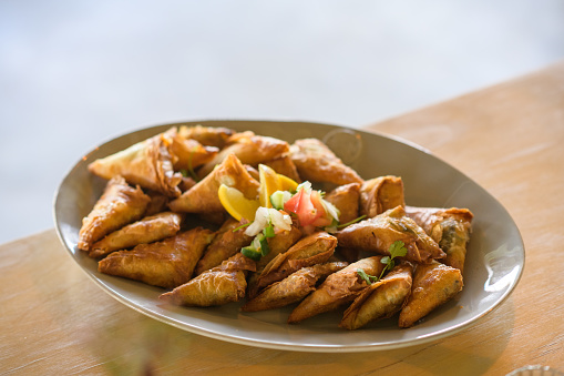 A plate of traditional deep fried samosas spanakopita triangles with garnish tapas canapés