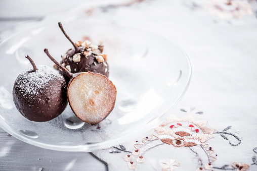 Poached Small Pears with Melted Chocolate and Almonds on Glass Plate