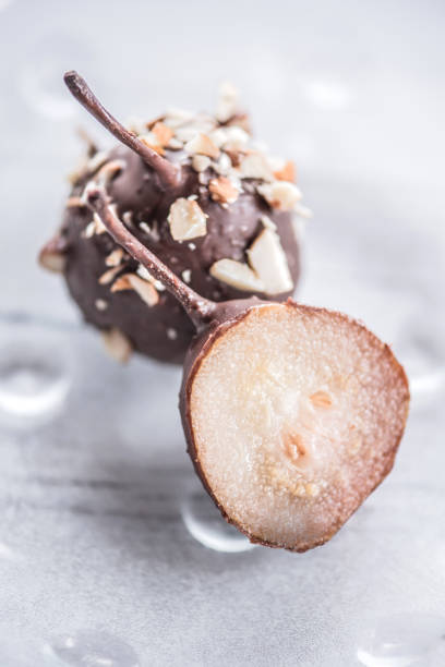 Poached Small Pears with Melted Chocolate and Almonds on Glass Plate