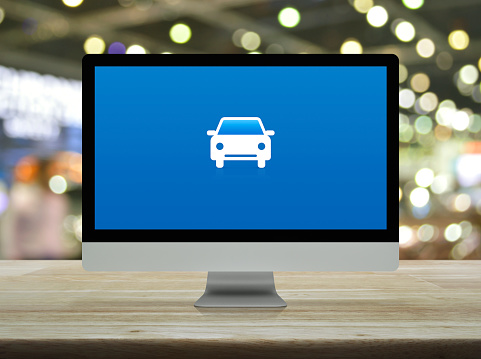 Car flat icon on desktop modern computer monitor screen on wooden table over blur light and shadow of shopping mall, Business transportation service online concept