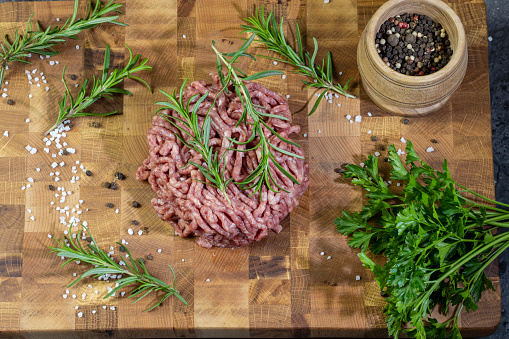 Fresh raw minced meat, ground beef, minced meat with herbs and spices on a wooden board.