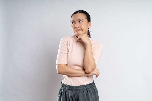 asian woman shrugs her arms and makes gesturing of she don't know isolated over white background. - rudeness ugliness clothing people imagens e fotografias de stock