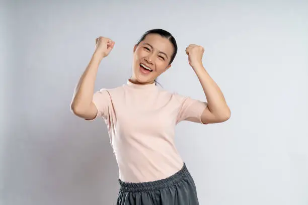 Photo of Asian woman happy confident showing her fist make a winning gesture.