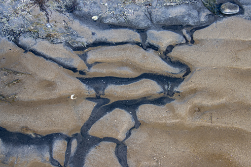 Black and brown sand forming a natural pattern during low tide in the north sea