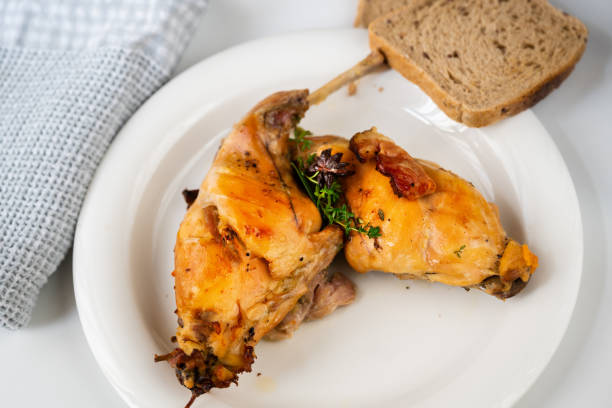 Baked rabbit thigh on plate, bread and towel on white plate. stock photo