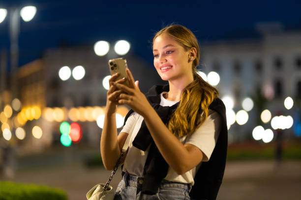 istock Young woman using smartphone in city at night 1415133193