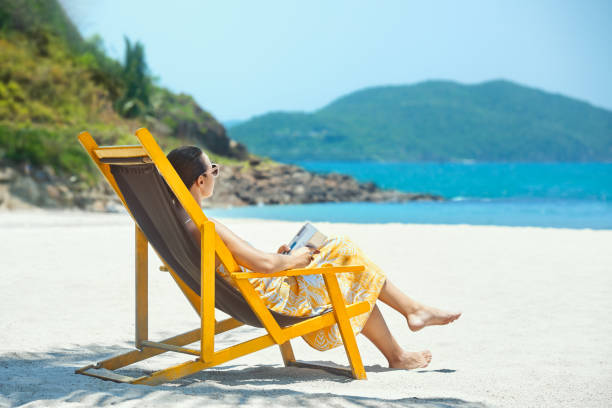 istock Woman reading book at beach resort during summer vacation. 1415133228
