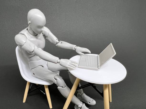 istock Wooden doll and typewriter working on a white chair in a room. Work/remote work concept. 1415133982