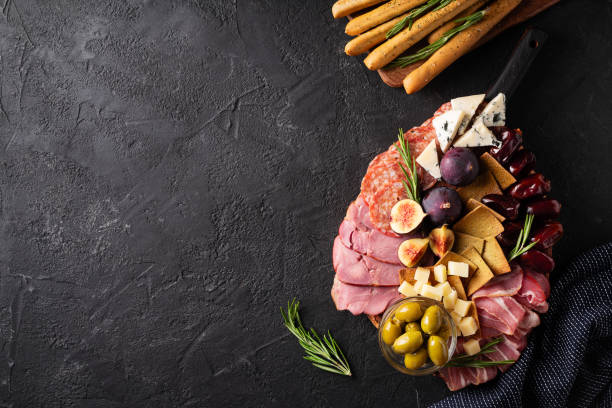 istock Meat, cheese and snackes plate, board and grissini on black background 1415134360