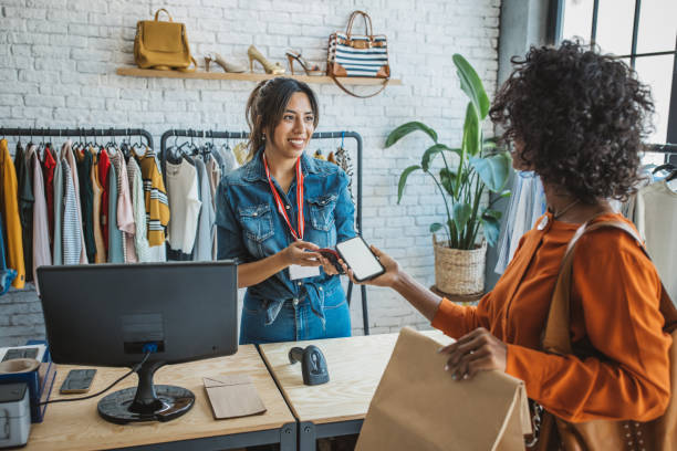 Sustainable shopping Customer at thrift store making a mobile payment. boutique stock pictures, royalty-free photos & images