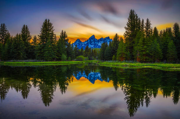 Sunset over Schwabacher Landing in Grand Teton National Park, Wyoming Sunset over Schwabacher Landing with Teton Mountain Range reflected in the waters of Snake River in Wyoming, USA. Long exposure. wilderness photos stock pictures, royalty-free photos & images