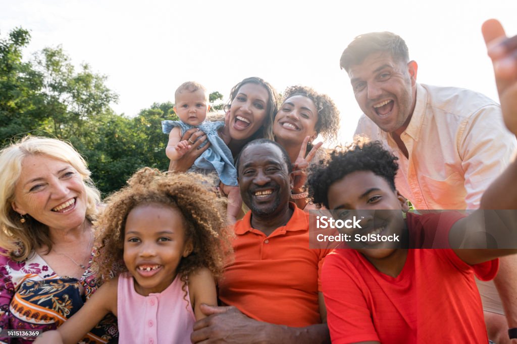 Cute Family Selfie! A front-view selfie shot of a multi-generation family standing together getting their photo taken, they are smiling and feeling happy on a summers day. Selfie Stock Photo