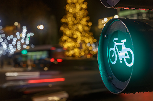Madrid Spain. December 25, 2021. Close shot of green traffic light for bicycles with traffic and Christmas decorations in the background