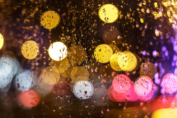 vidrio con gotas de lluvia contra luces nocturnas desenfocadas - nightlife city night rain fotografías e imágenes de stock