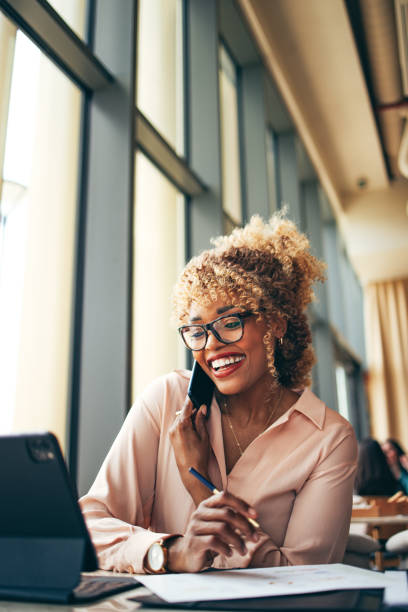 smiling businesswoman talking on a mobile phone in the cafe - digital tablet women enjoyment happiness imagens e fotografias de stock