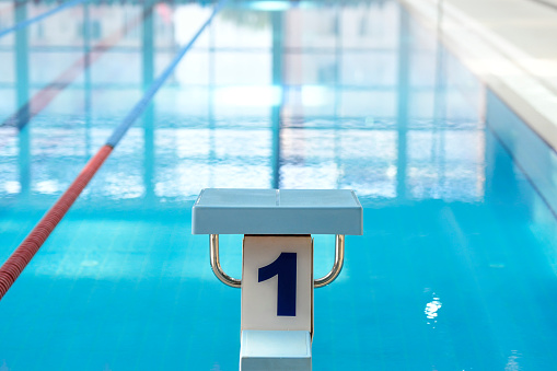 Athletic Young Female Swimmer Comes to Starting Block and Prepairing to Jump into Swimming Pool. Healthy Professional Woman Athlete Training for the Championship. Wide Shot