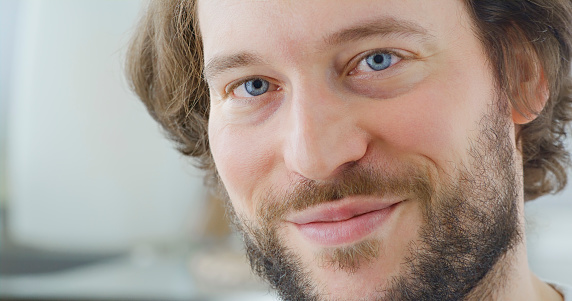 Close-up of smiling man with blue eyes and beard looking into camera.