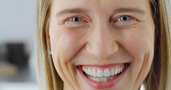 Close-up of smiling senior woman with grey eyes looking into camera.