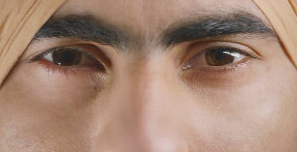 Close-up of young man with brown eyes looking at camera.