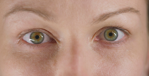 Close-up of woman with hazel eyes looking at camera.