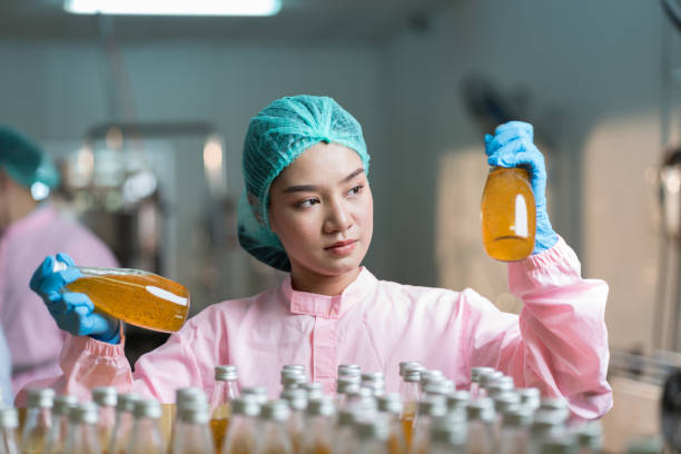 istock Asian woman worker checking product bottles basil seed with fruit on shelf pallet parcel in the beverage factory. Manufacturer and Inspection quality control 1415145445