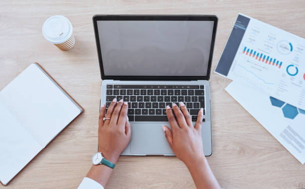 istock Digital marketing hands typing a report on a blank computer. Female office worker looking at finance graphs for work. Above view of a business woman working on a laptop while doing online research 1415147609