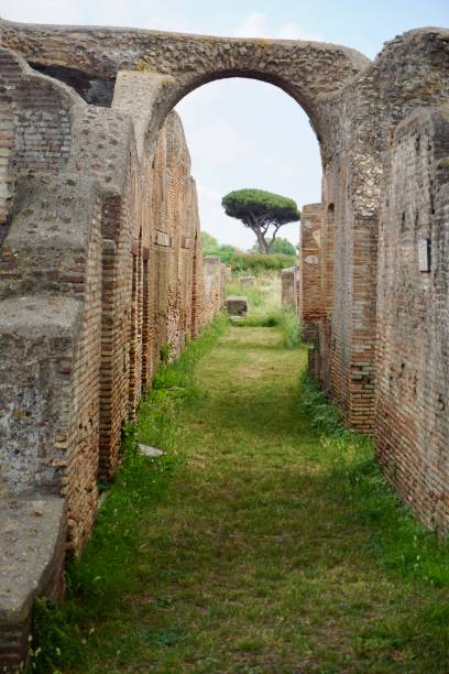 ostia antica to duże stanowisko archeologiczne, w pobliżu współczesnego miasta ostia, czyli lokalizacji portowego miasta starożytnego rzymu, 15 mil (25 kilometrów) na południowy zachód od rzymu. - roman column arch pedestrian walkway zdjęcia i obrazy z banku zdjęć