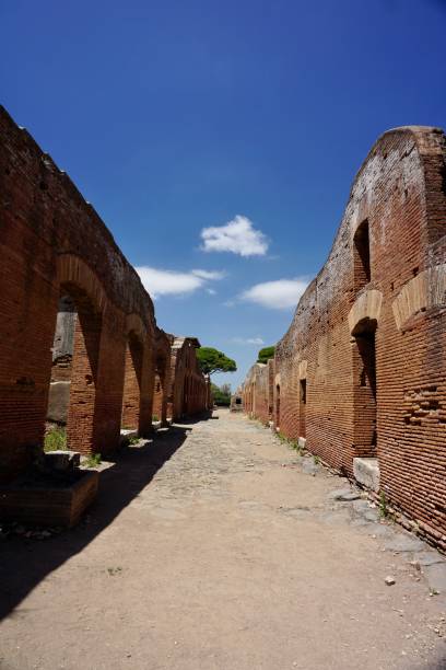 ostia antica to duże stanowisko archeologiczne, w pobliżu współczesnego miasta ostia, czyli lokalizacji portowego miasta starożytnego rzymu, 15 mil (25 kilometrów) na południowy zachód od rzymu. - roman column arch pedestrian walkway zdjęcia i obrazy z banku zdjęć