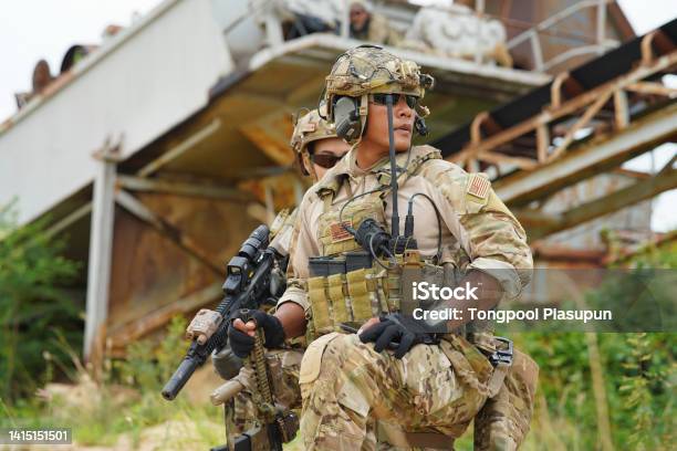 Soldier In The Battle Field Sitting Knee Down On The Ground Hold The Gun Alert Look Around Stock Photo - Download Image Now