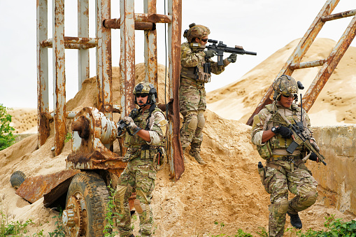 Army military soldier in the battle field claim up to steel structure for security check while team hold the gun alert look around ready to fire weapon
