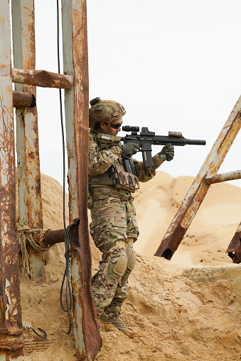 Army military soldier in the desert battle field hold the short hand gun to enamy