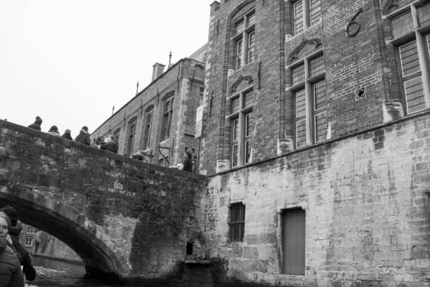 turistas fazendo o passeio de barco no canal de bruges, rodeado por edifícios flamengos da bélgica - bruges cityscape europe autumn - fotografias e filmes do acervo