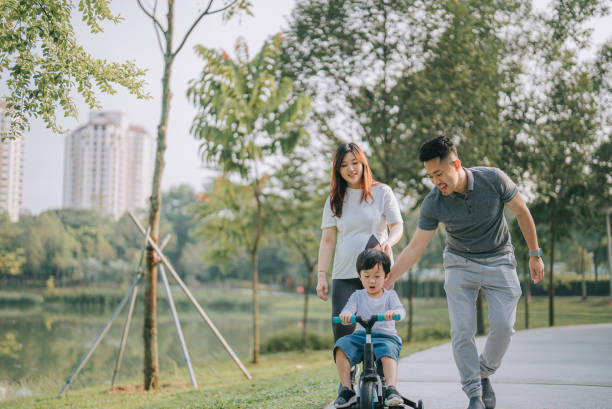 주말 아침에 부모님과 함께 공공 공원에서 사이클링을 배우는 아시아 중국인 소년 - park child asia lifestyles 뉴스 사진 이미지