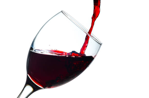Pouring red wine into a glass isolated on white background stock photo