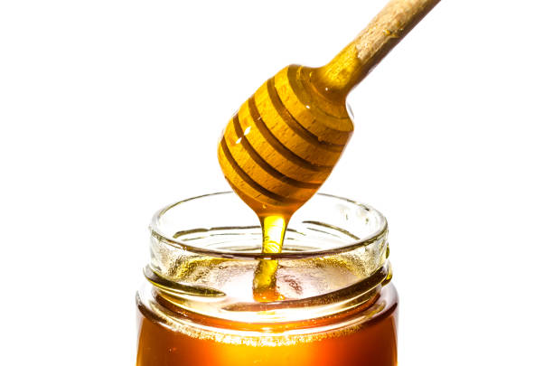 Dripping honey in a glass jar isolated on white background stock photo