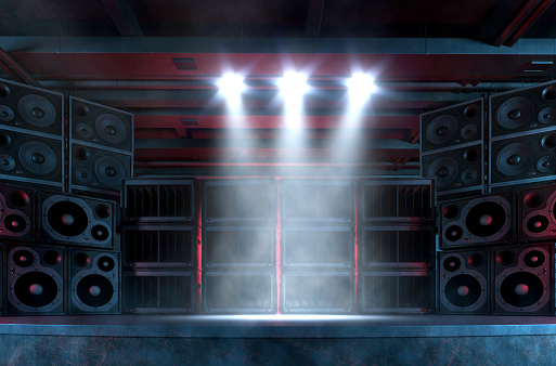 Empty music concert stage illuminated by bright spotlights, with foggy and smokey atmosphere, surrounded by a large and loud sound system with plenty of loudspeakers. Punk and hard rock music background. Digitally generated image with copy space.
