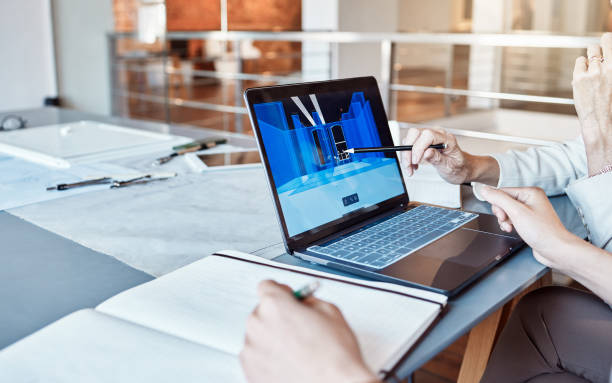Architect, design engineer or contractor pointing to a 3d digital model on a laptop screen, discussing a plan or idea with a colleague in a meeting. Business people talking about a work project