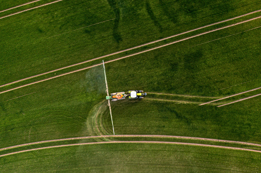 top down view of the tractor spraying the chemicals on the large green field, agriculture concept