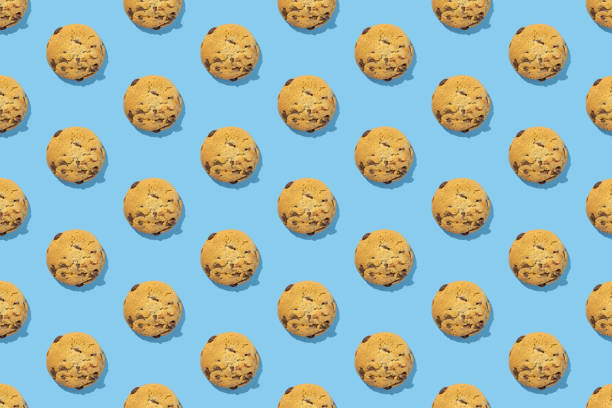 istock Pattern of sweet chocolate cookies on blue background with hard shadows. Flat lay 1415163741