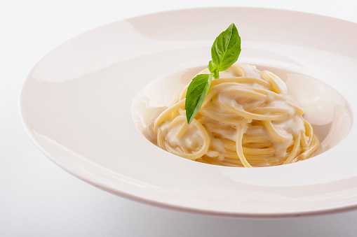 Spaghetti with white cream sauce on white plate