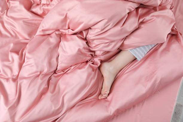 Young woman sleeping in comfortable bed with silky linens, closeup