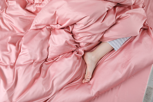 Young woman sleeping in comfortable bed with silky linens, closeup